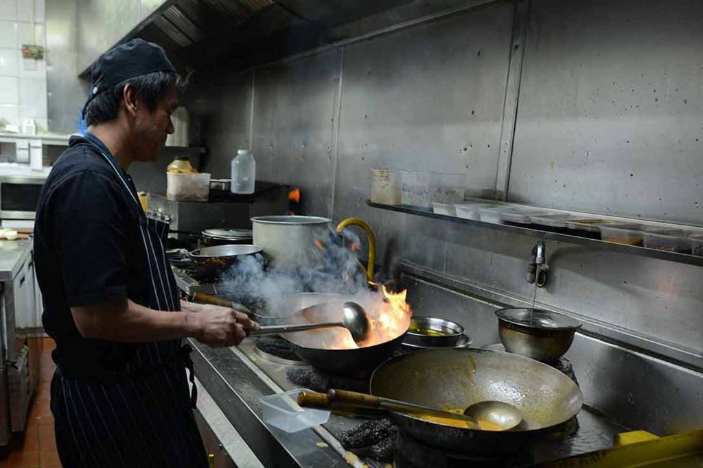 Cooking in different pans to cater for gluten-free dietary needs, at an Indian restaurant in Brick Lane, London.