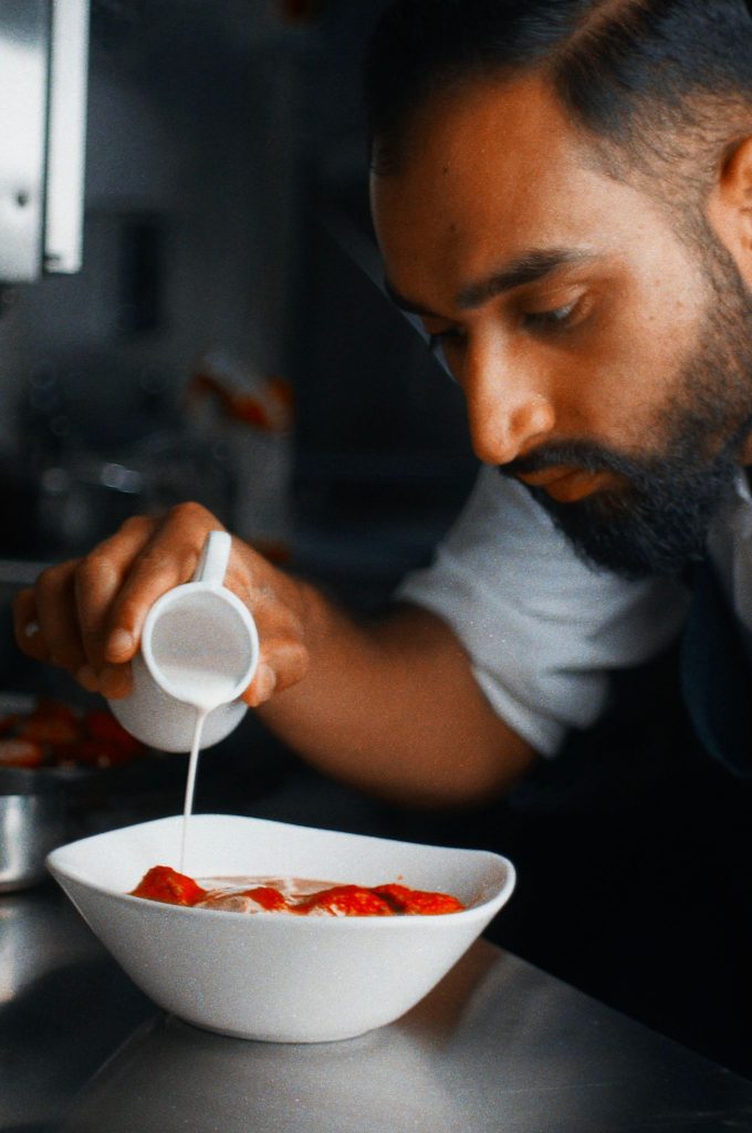 Chef Niaz Caan pouring cream over one of his dishes.